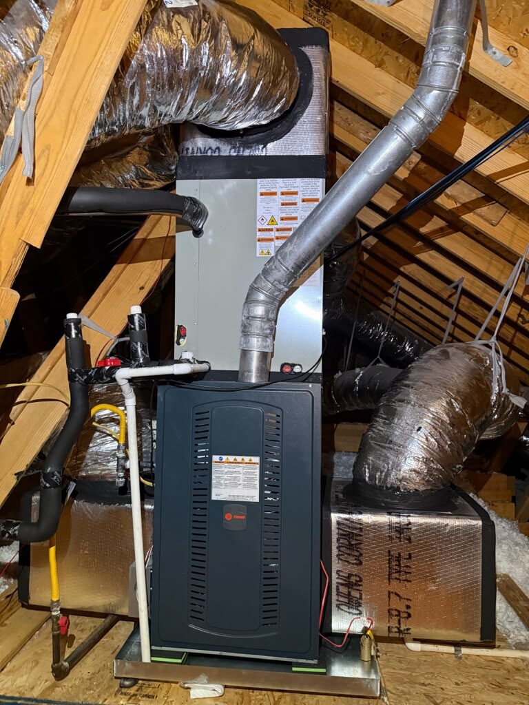A Trane furnace and coil in an attic, with a new vent pipe, gas line and insulated ducts.
