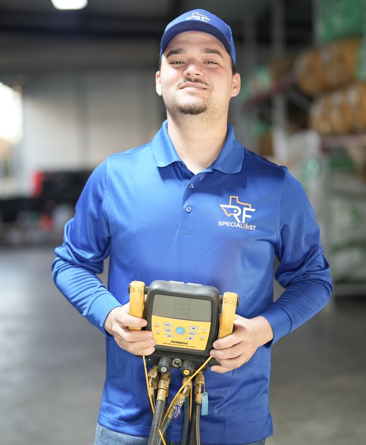 An RF technician holding a digital refrigerant gauge in the warehouse.