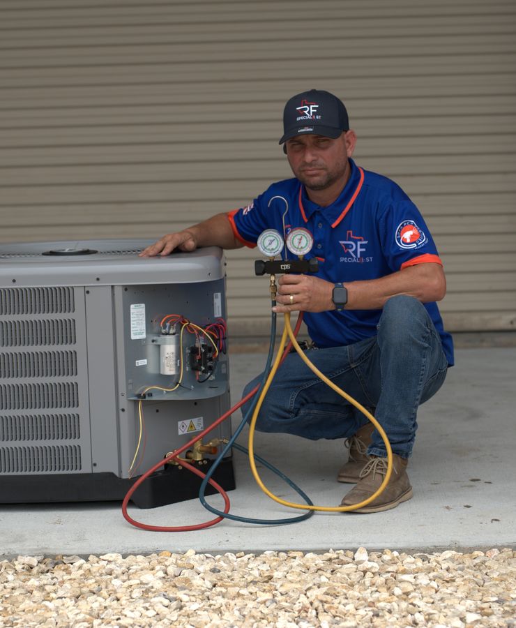 An RF technician crouched beside a condensing unit with a manifold gauge set.