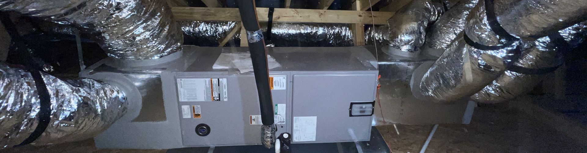 An attic equipment platform with an indoor unit connected to insulated flex ducts.