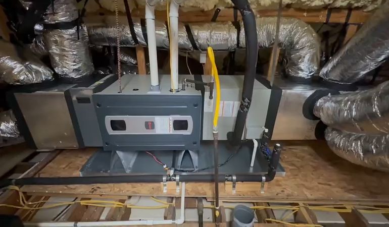 A furnace installation in an attic, centered between insulated supply ducts.