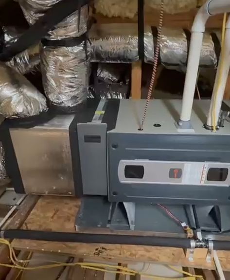 The side of an attic furnace with its vent pipes and gas connection.