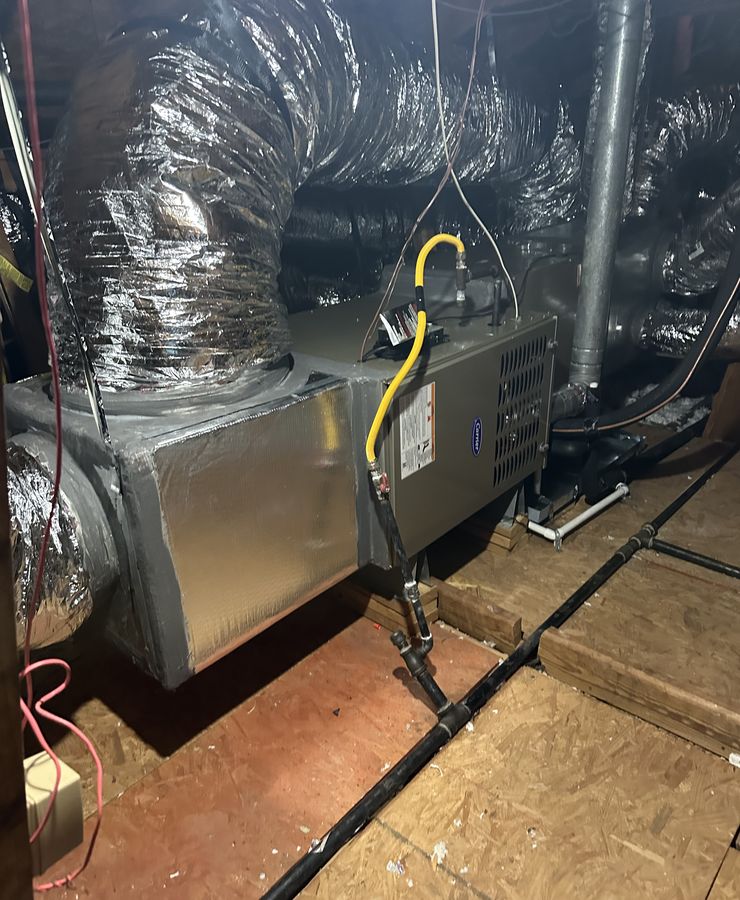 A gas furnace installed in an attic with its gas line and insulated flex ducts.