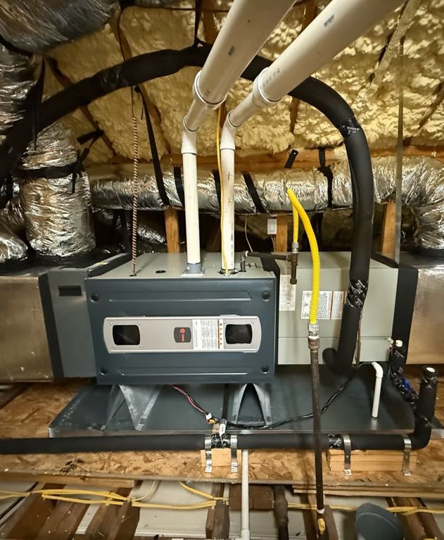 A gas furnace on a platform in an attic, with new venting, a gas line and insulated ducts.