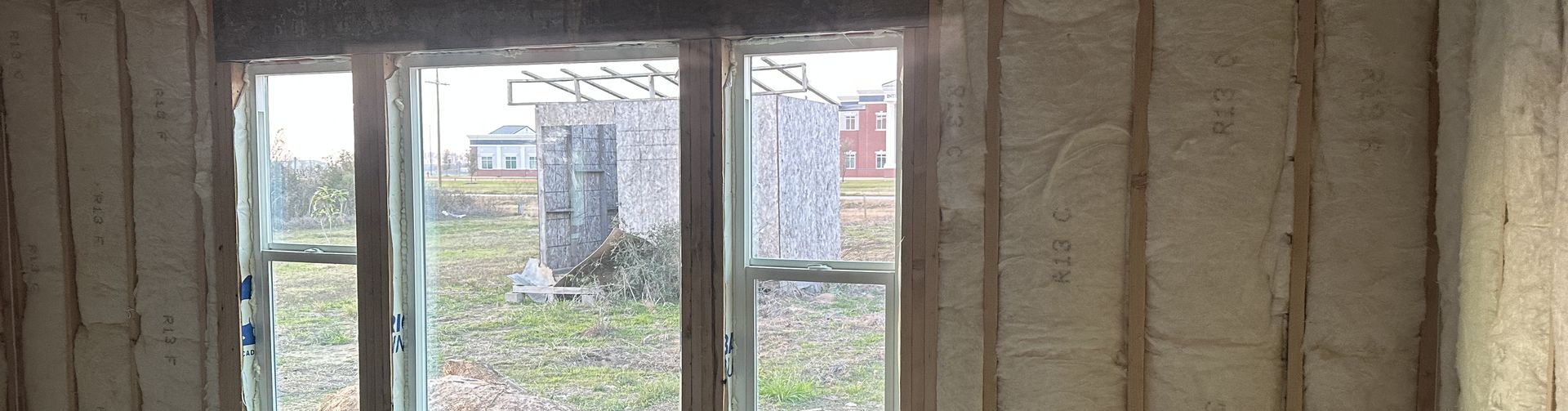 A framed wall sealed with spray foam insulation around the window openings.