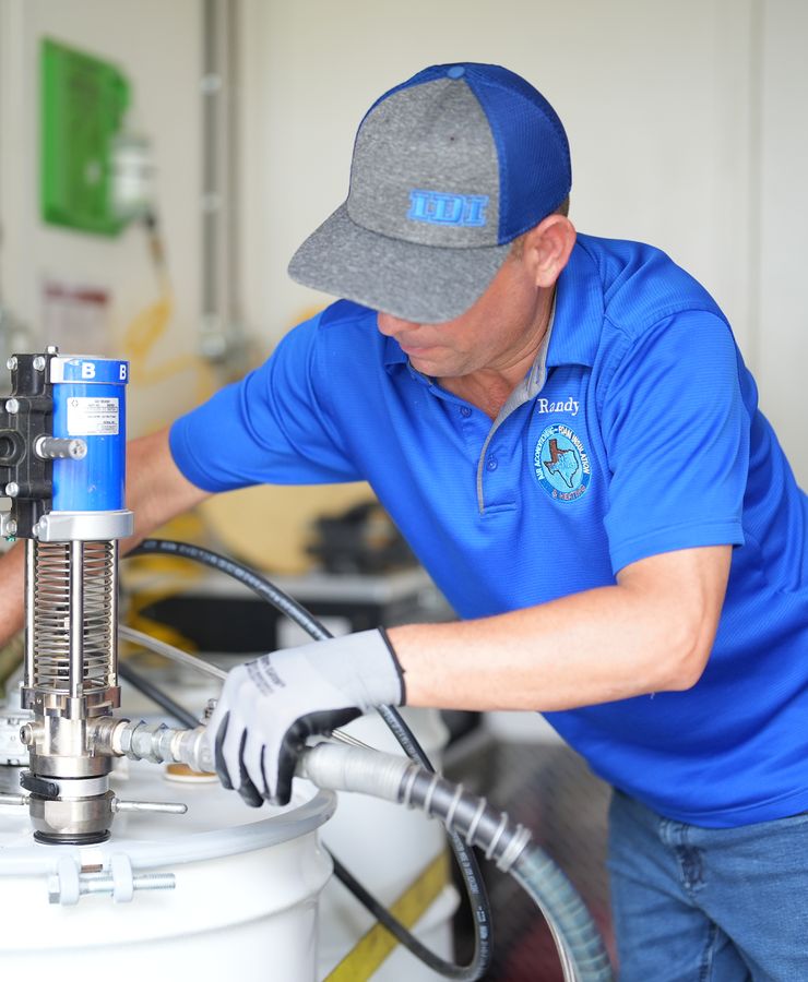 A technician servicing the spray foam pump on a material drum.
