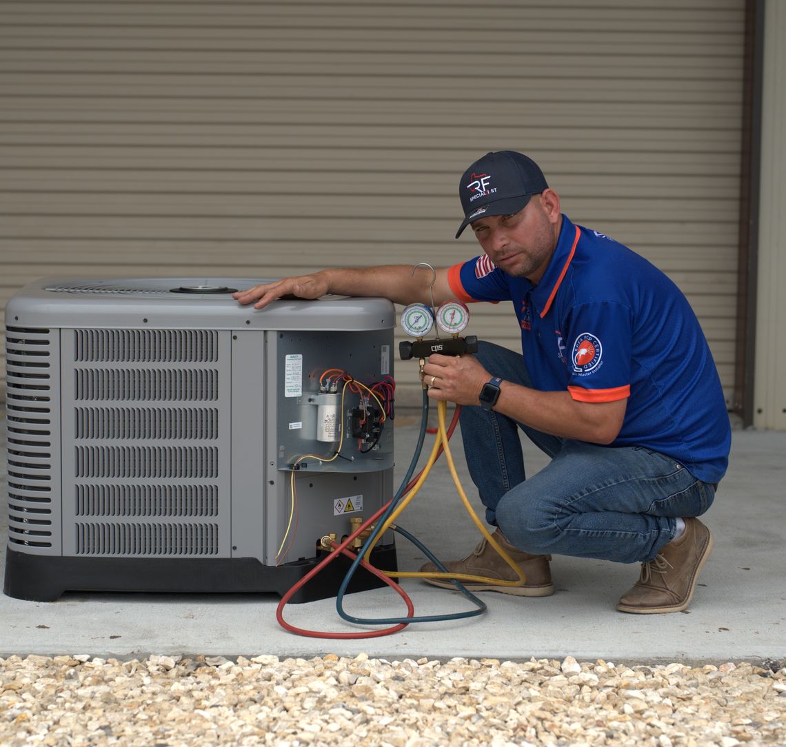 An RF technician reading a manifold gauge set during maintenance on a condensing unit.